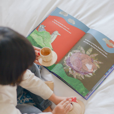 Little girl reading children's book on a bed